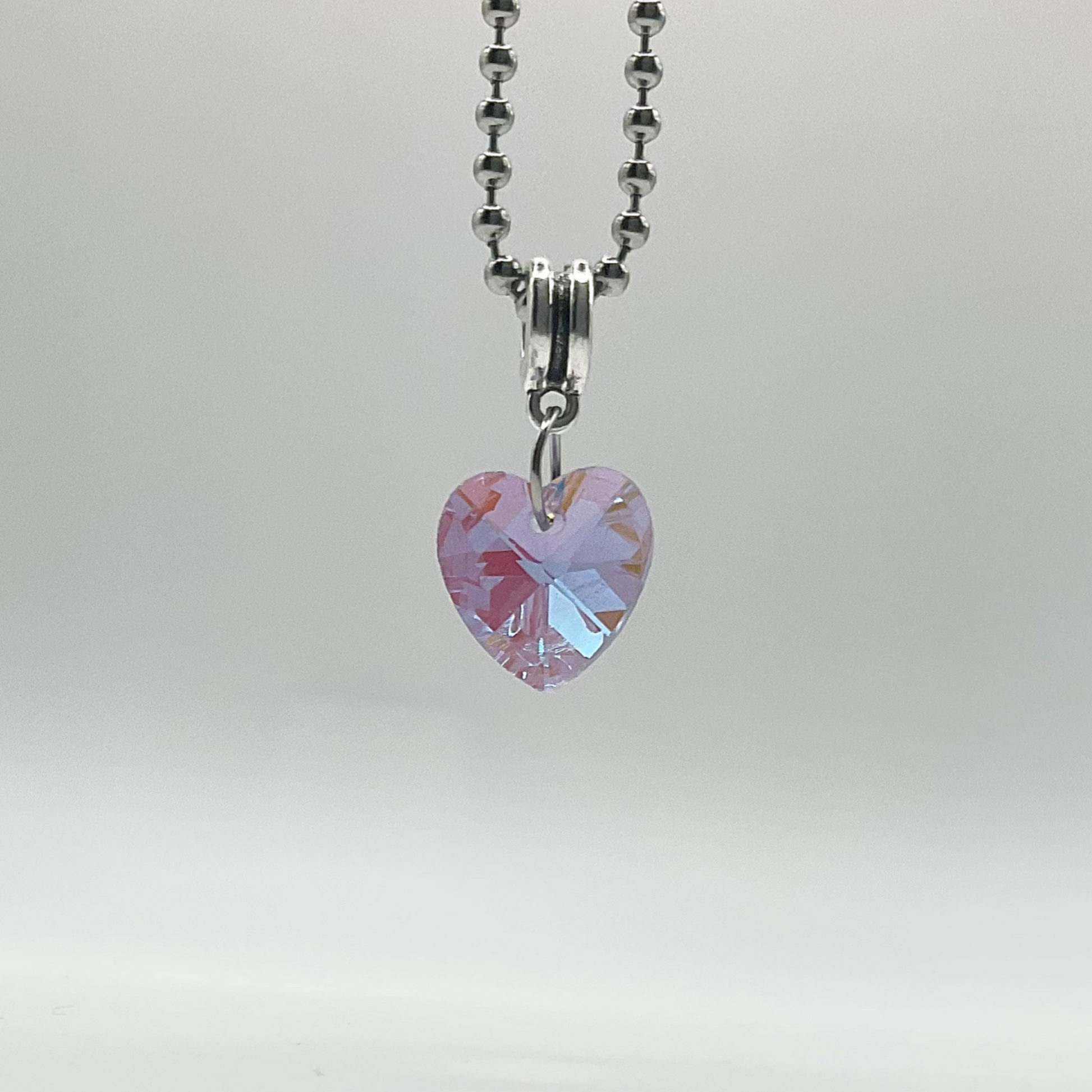 Charm Necklace with a purple tinted heart-shaped crystal pendant on a gray background