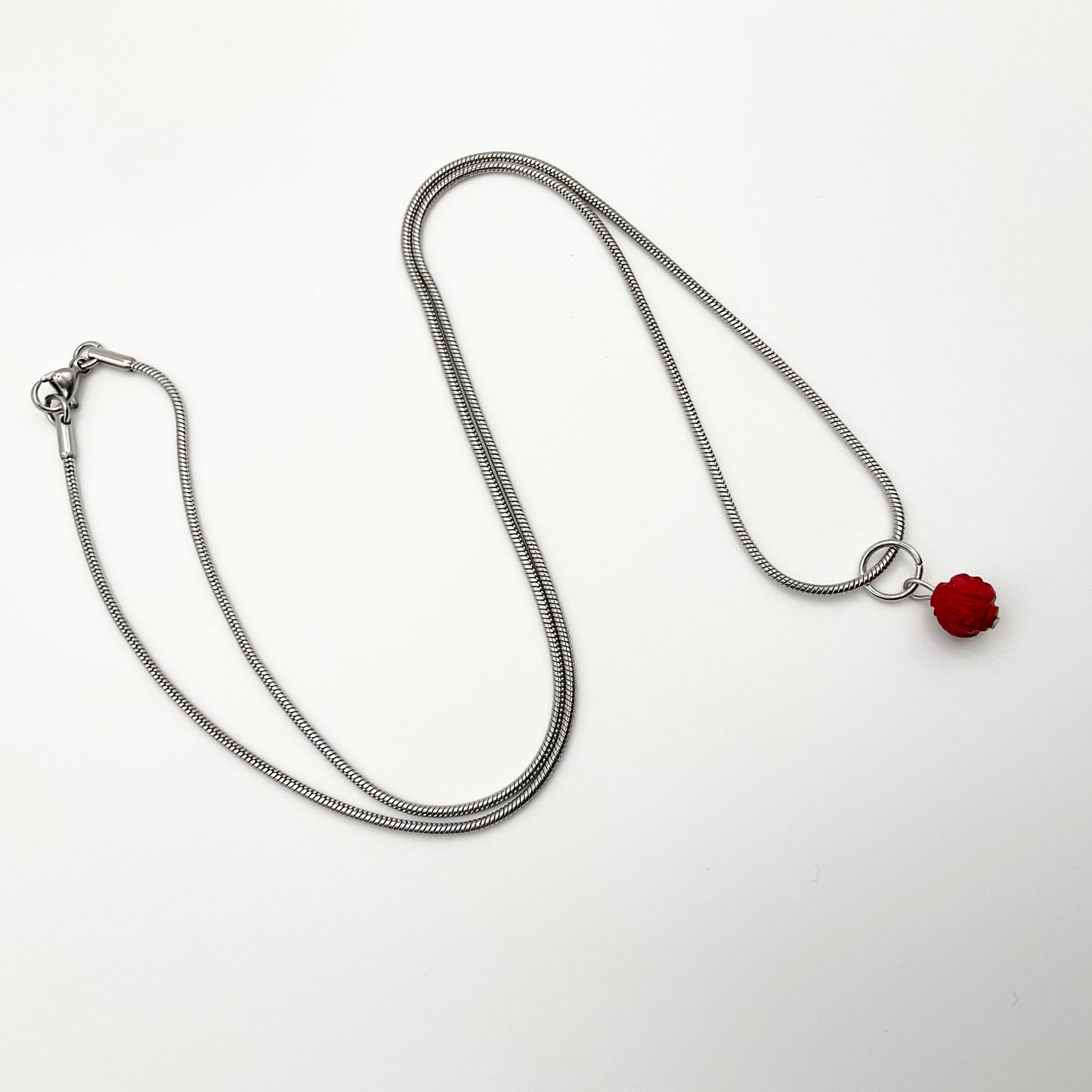 Silver tone necklace with a red coral pendant on a white background