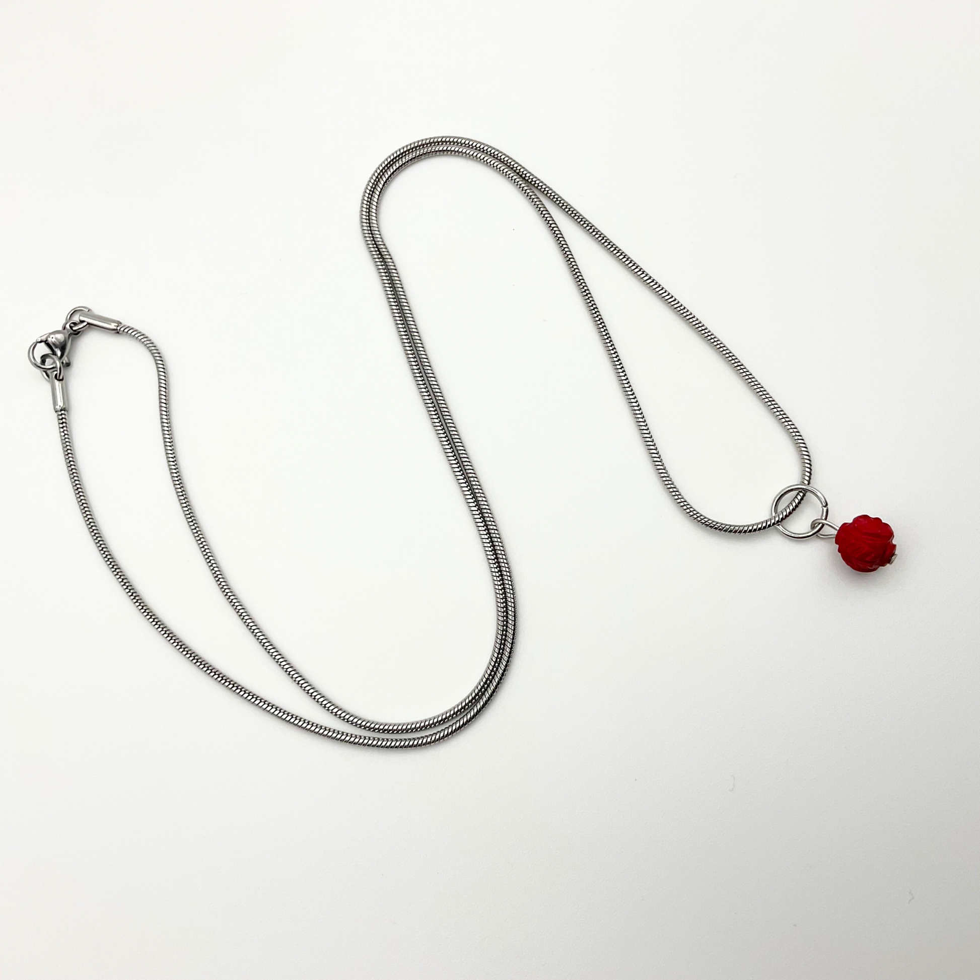 Silver tone necklace with a red coral pendant on a white background