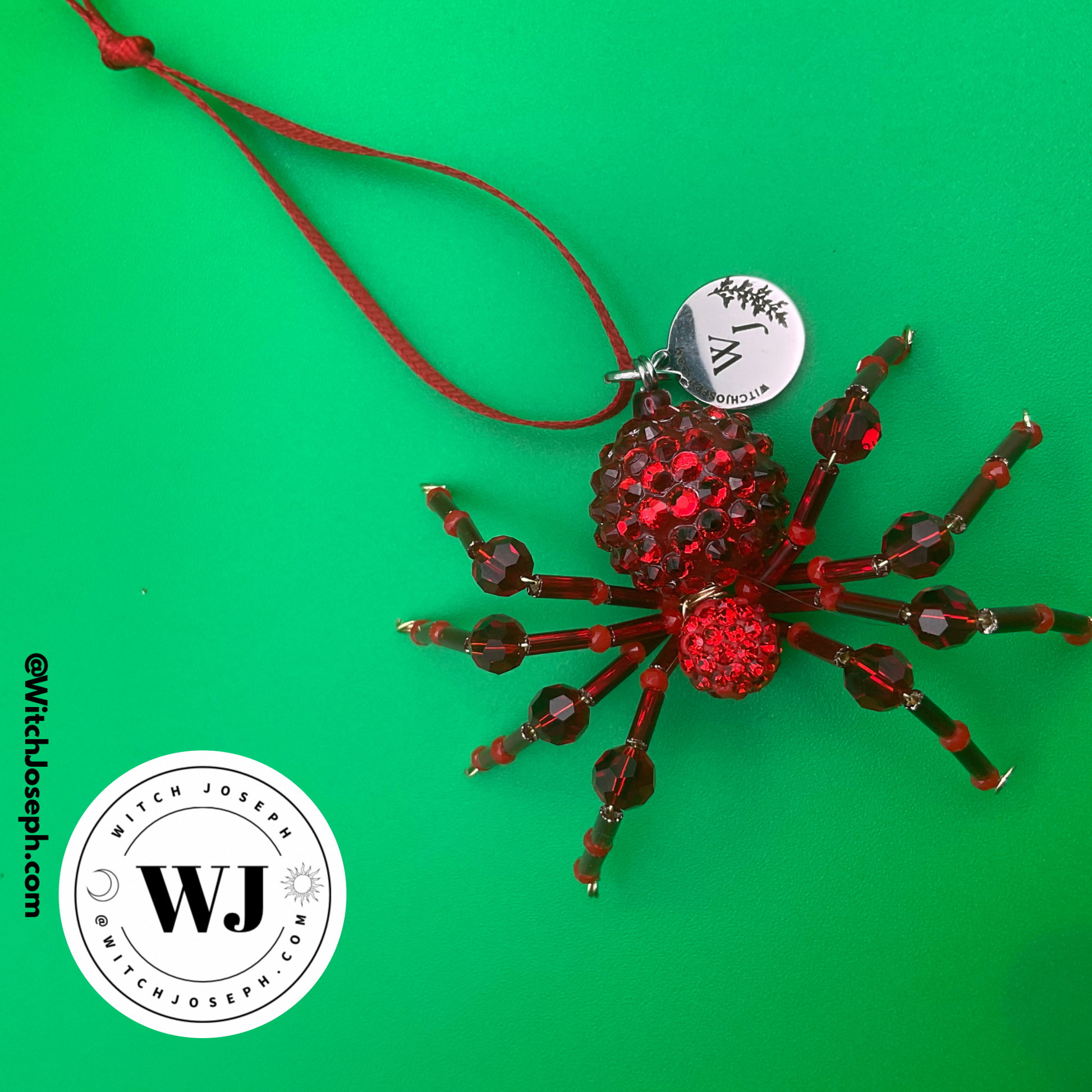 red spider holiday ornament on green background with the Witch Joseph logo