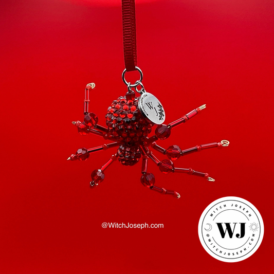 Red holiday spider ornament displayed on a red back ground with the Witch Joseph logo