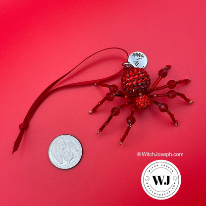 Red spider ornament for the holiday displayed on a red back ground with a quarter for sizing…with the Witch Joseph logo