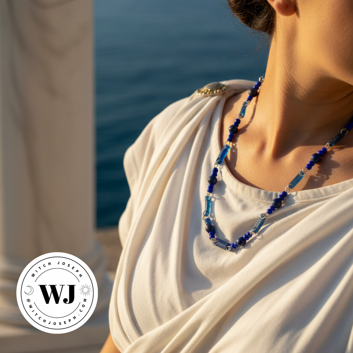 Roman Woman wearing a blue ancient Roman glass beaded necklace with lapis beads standing by the sea with the Witch Joseph logo