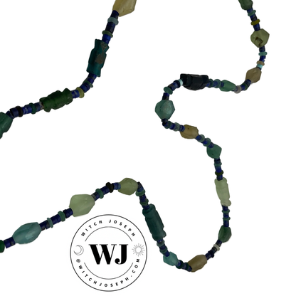 Beaded necklace with green and blue Roman glass beads and lapis lazuli displayed on a white background, featuring the Witch Joseph logo.