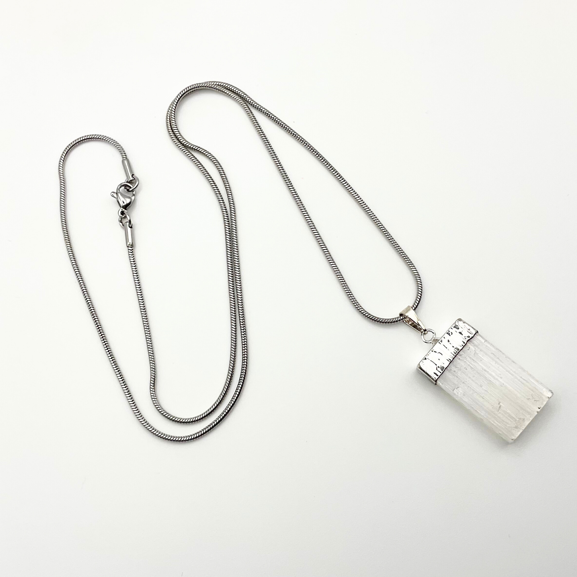 Silver necklace with a rectangular selenite pendant on a white background