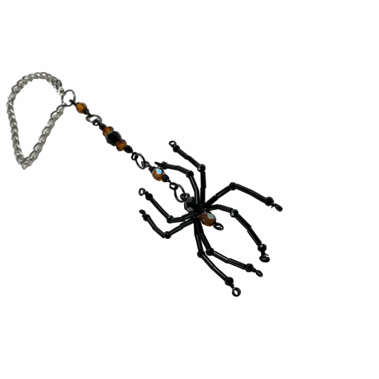 Black spider-shaped Sun Catcher with Orange bling accent beads on a chain against a white background