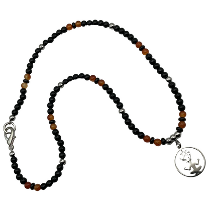 Necklace with black and orange beads and a silver tone cernunnos pendant on a white background