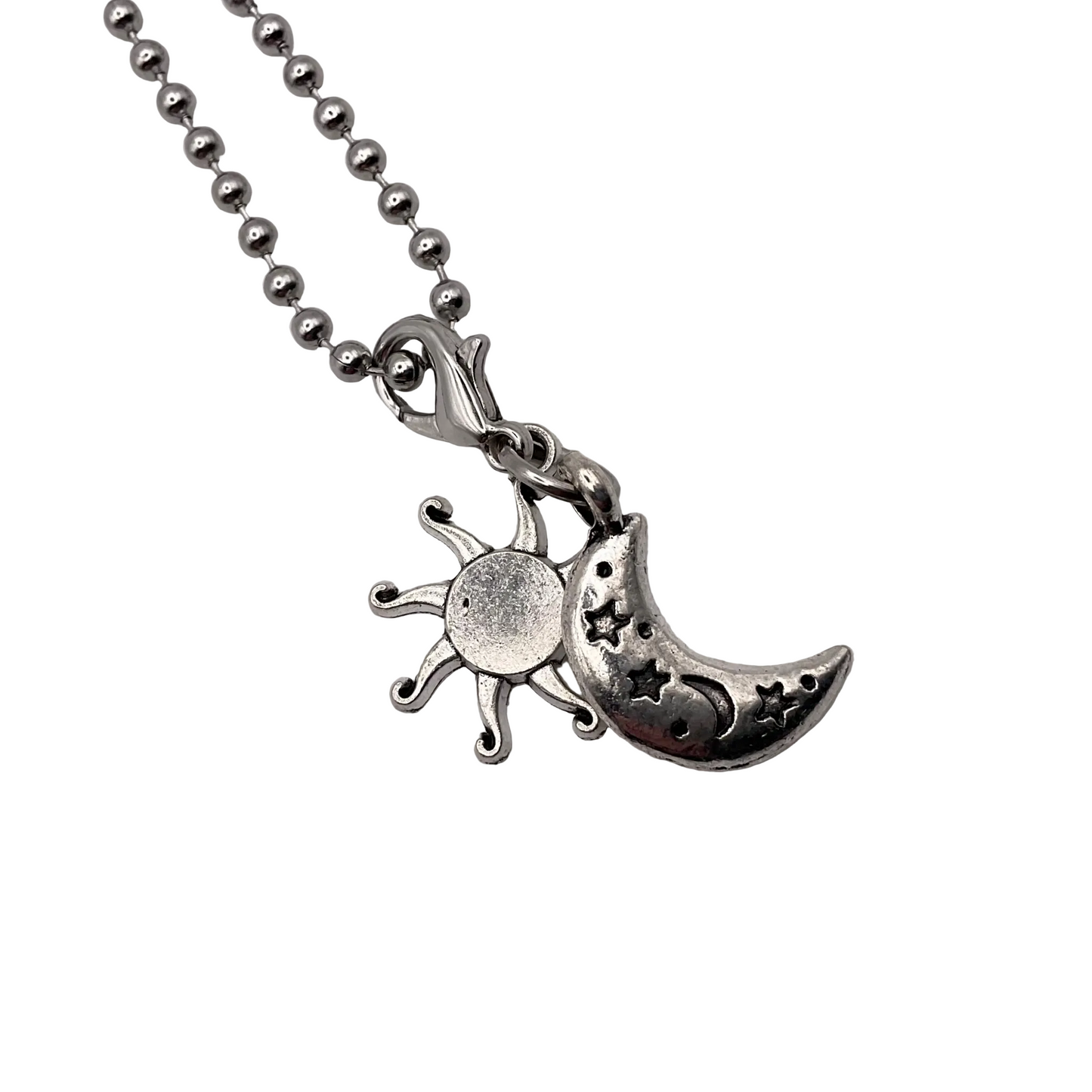 Silver tone necklace with sun and moon pendant on a white background.