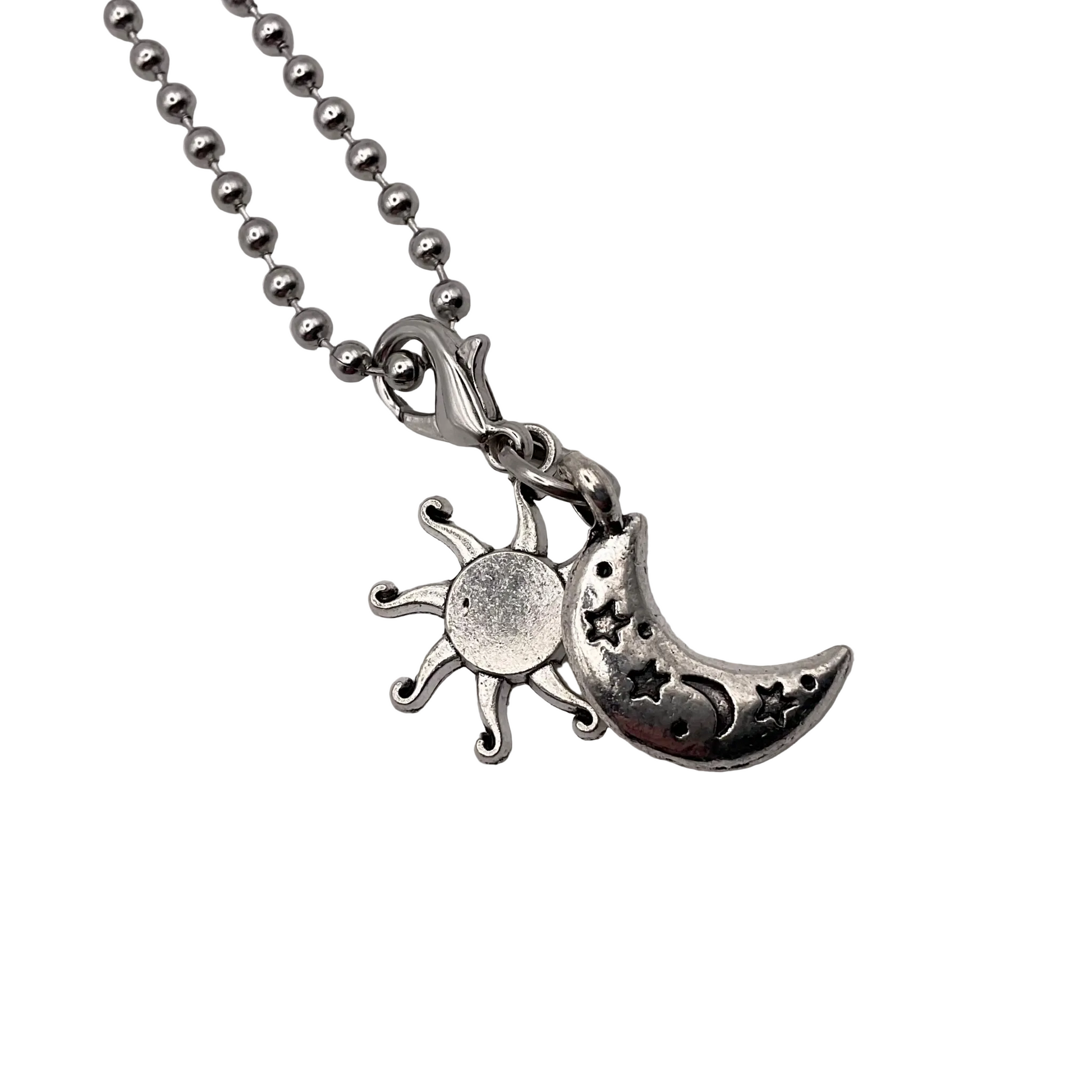 Silver tone necklace with sun and moon pendant on a white background.
