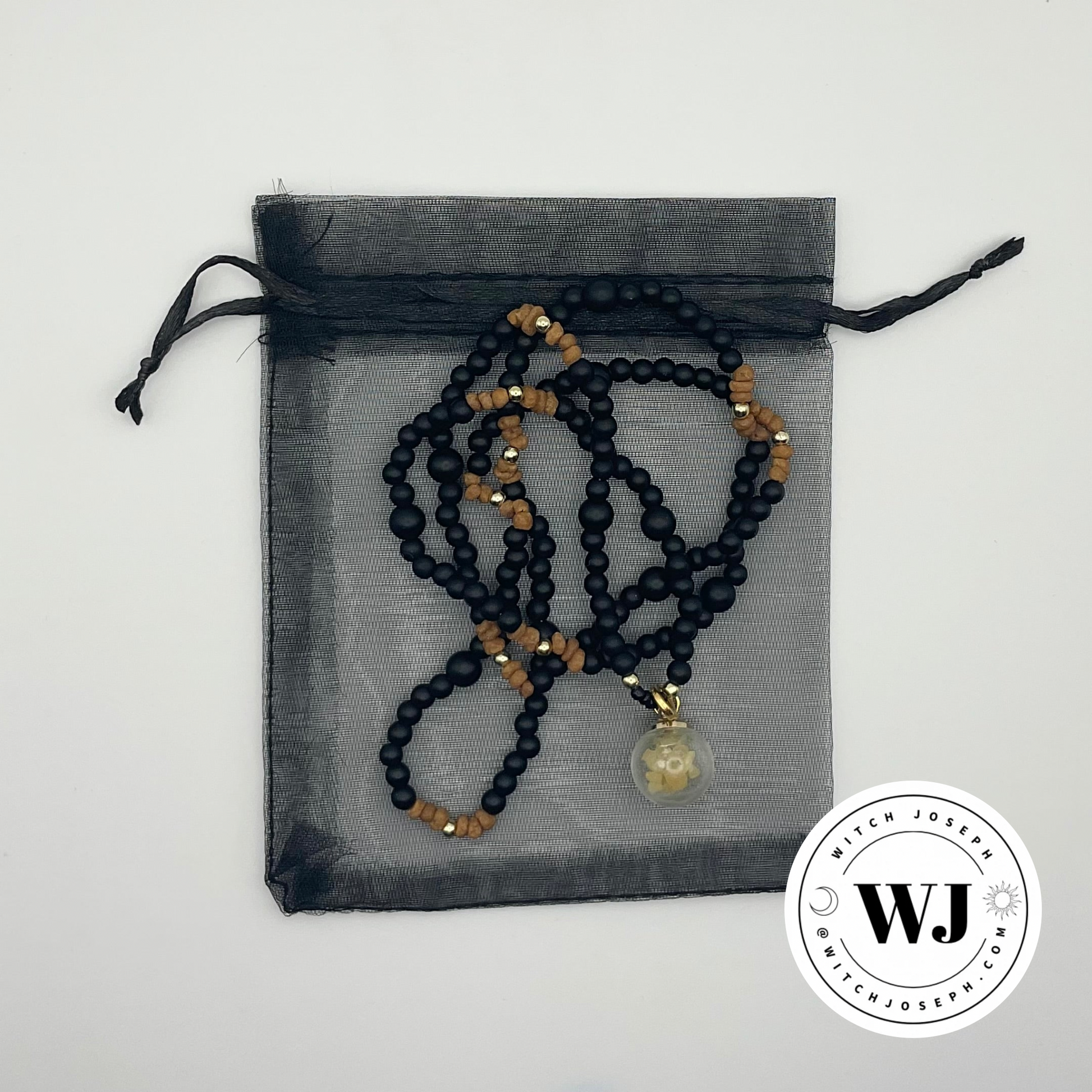three kings necklace shown on it’s black organza gift bag with the Witch Joseph logo