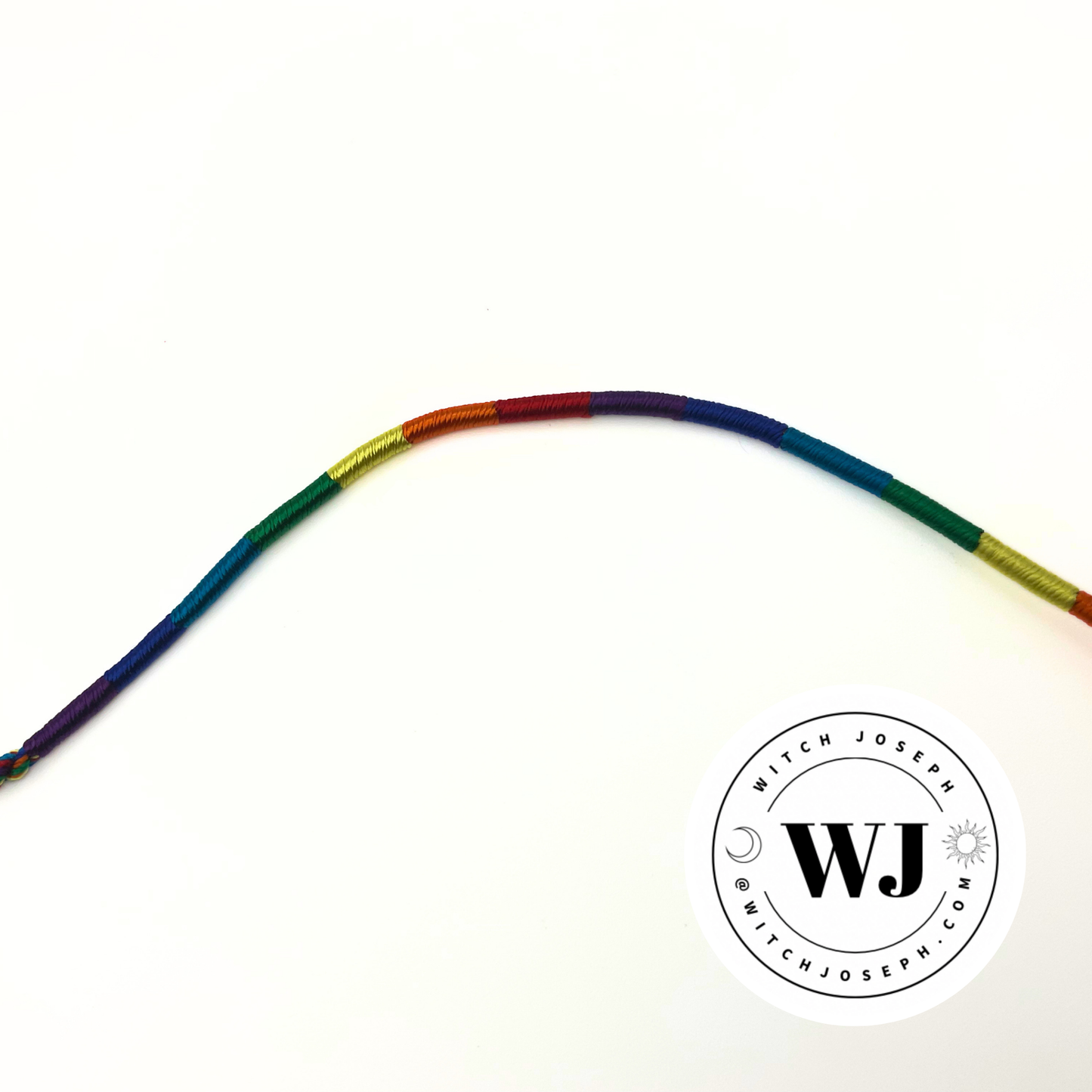 A curved rainbow-colored cord bracelet on a plain white background, with a circular 'Witch Joseph' logo watermark with the URL in the lower right corner.