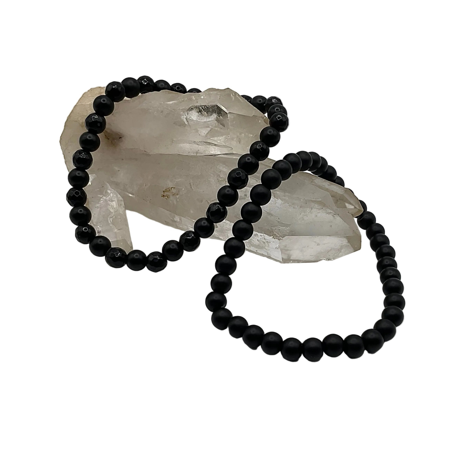 Two Black beaded bracelets on a white background displayed with a clear quartz crystal rock.