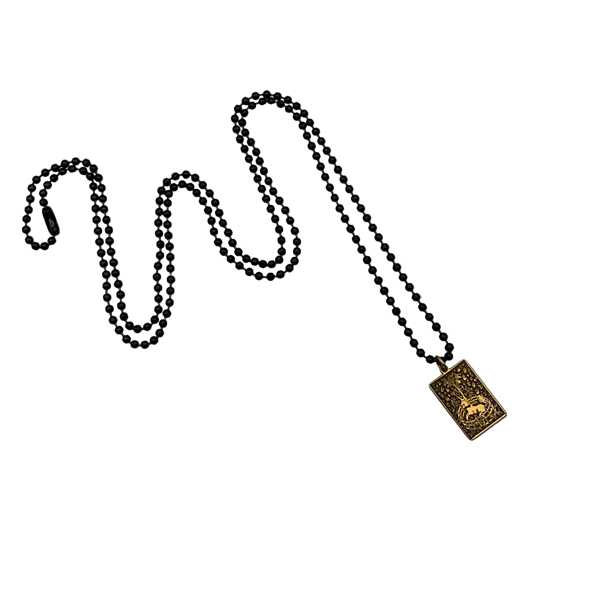 Black ball chain necklace with a brass Unicorn pendant on a white background