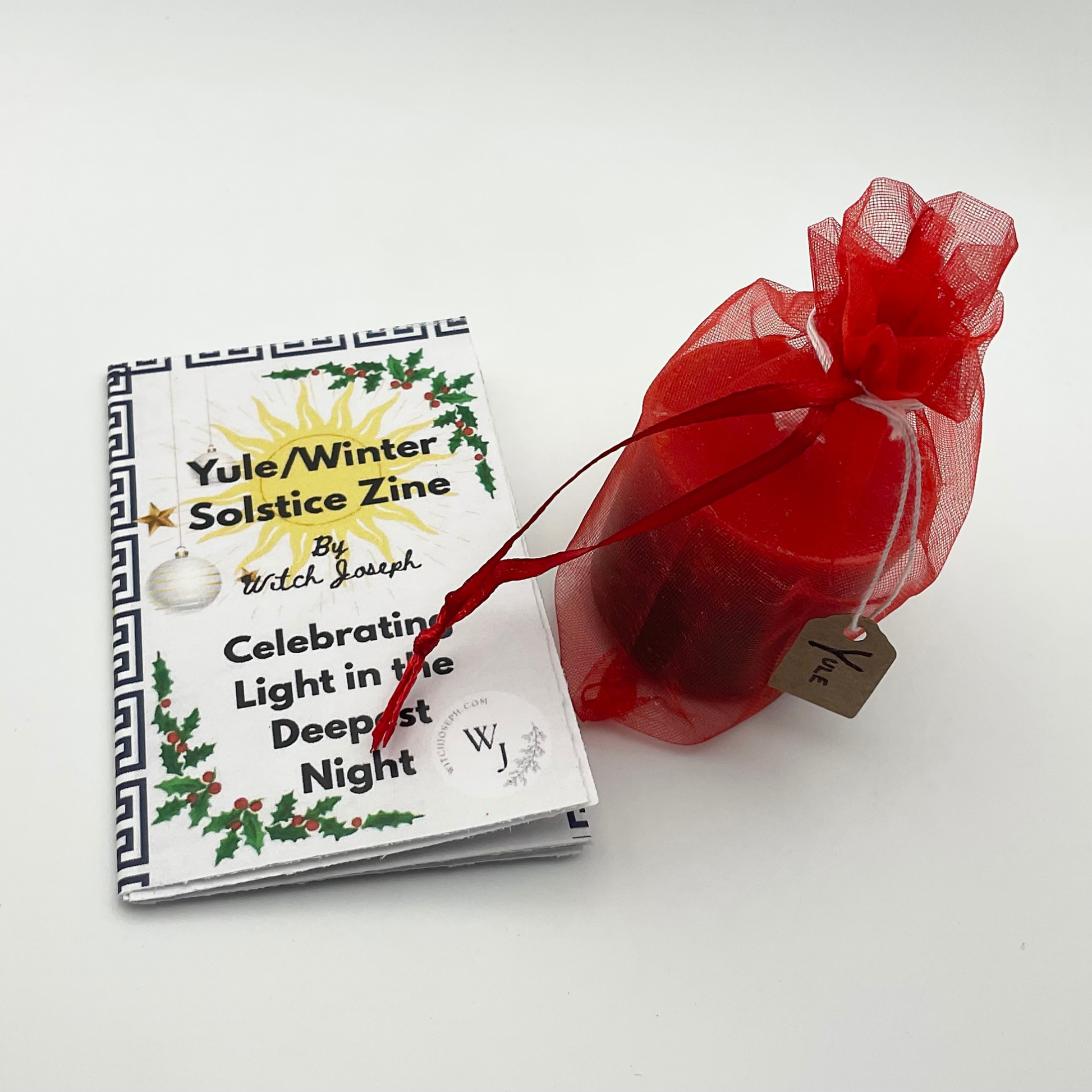 The Winter Solstice Sabbat kit items shown against a white background…the Yule candles in a red organza bag and the Yule Zine.