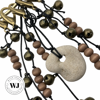 Door Charm with brown beads, pentacles, bells and a Holey stone…displayed  on a white background, featuring the Witch Joseph logo
