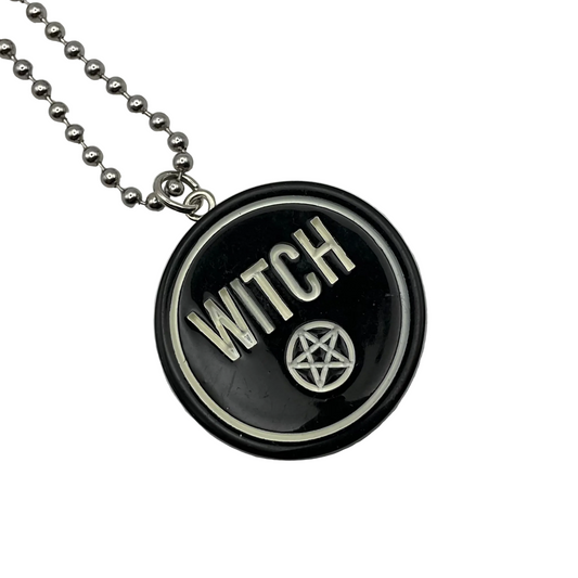 Black pendant with 'WITCH' and pentagram on a ball chain against a white background