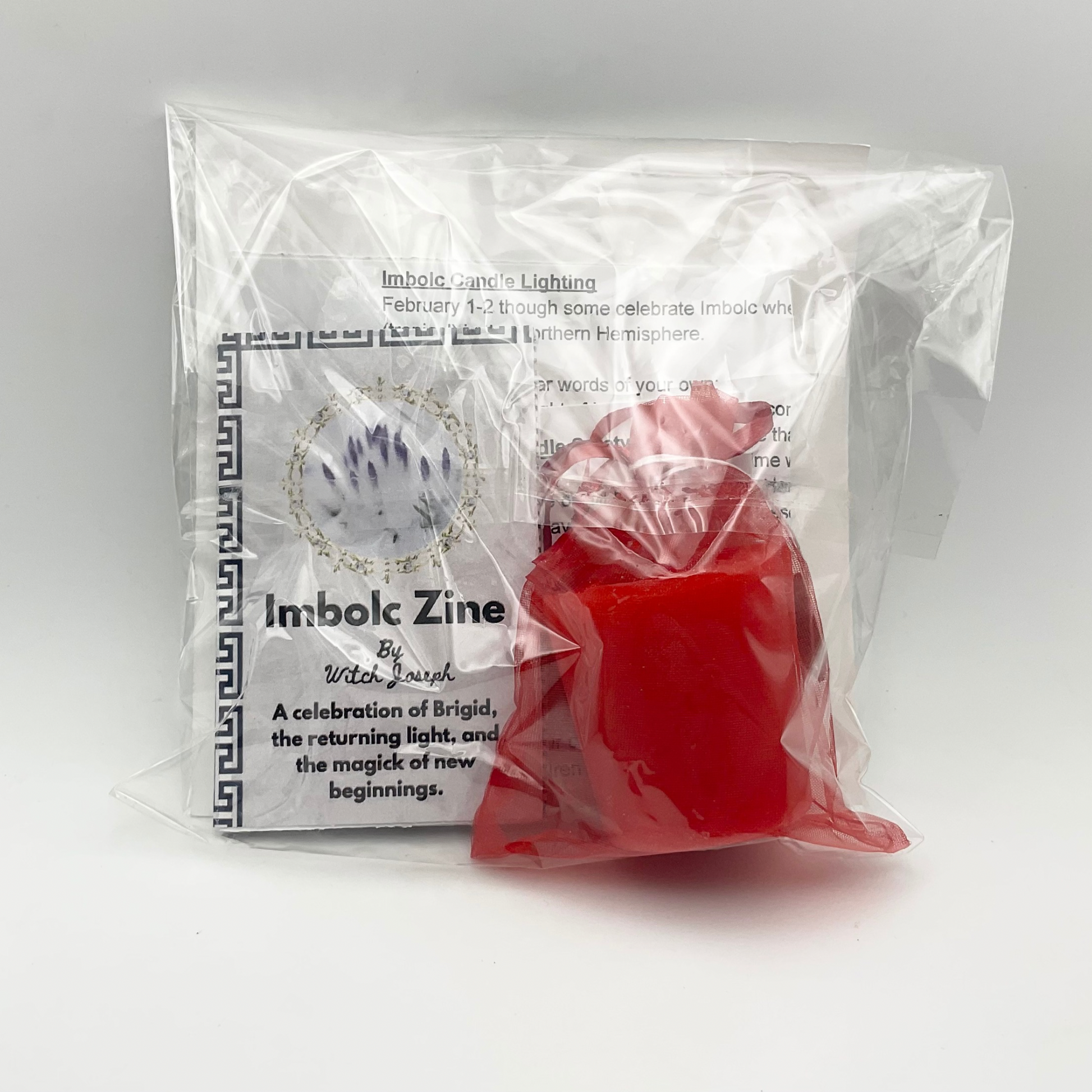 The Witch Joseph Imbolc Candle Lighting kit shown from the reverse side of the packaging which allows the candle, zine and other contents to be seen against a white background.