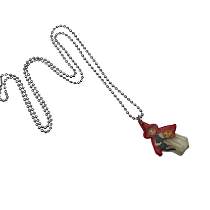 Necklace with a small pendant featuring a vintage style trick or treater character in a red hat holding a black cat and a jack o lantern pail on a light white background