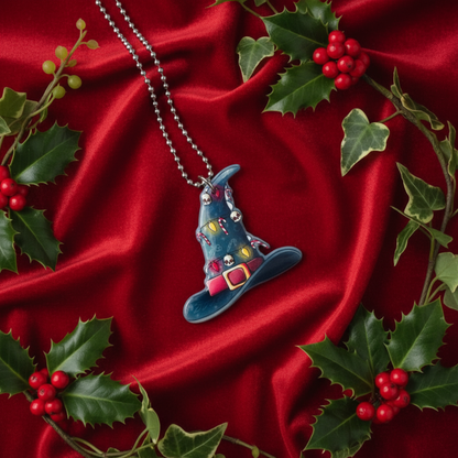 witch hat ornament pendant with gothic elements on a ball chain displayed on a red satin background with holly leaves and berries