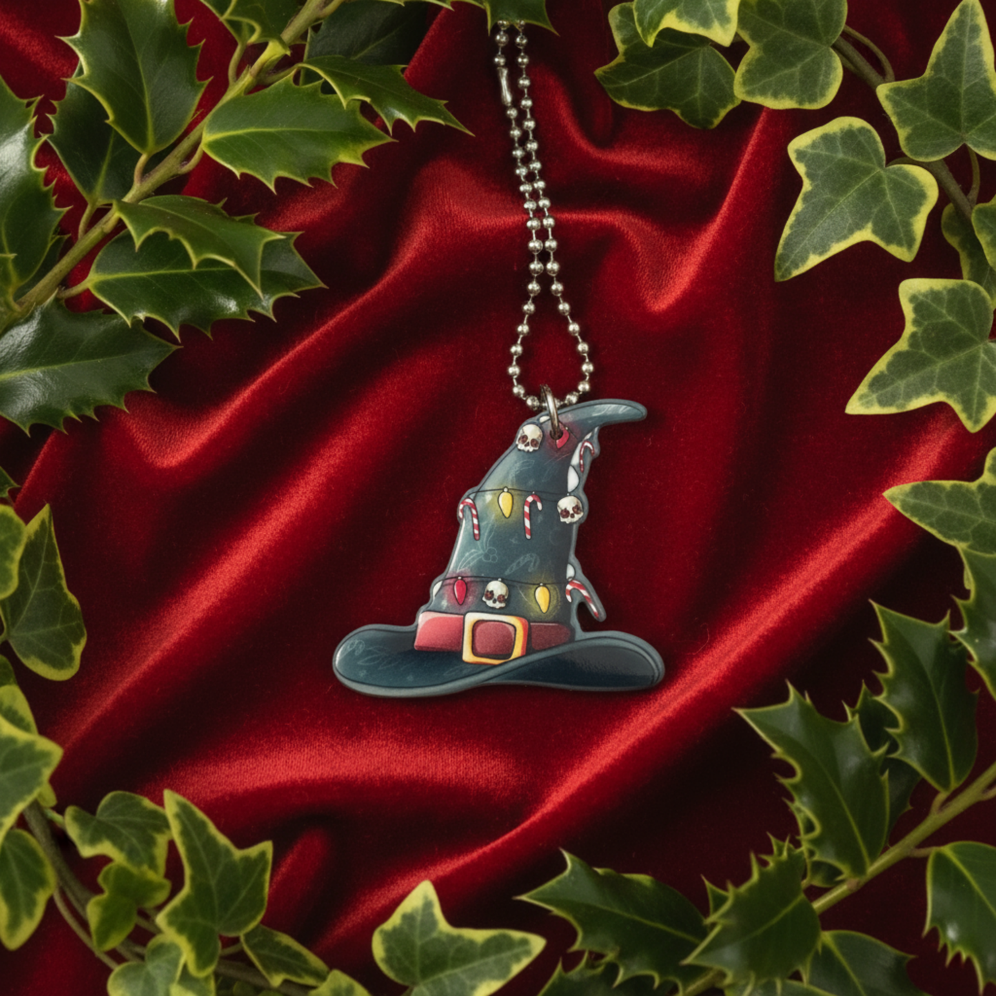Witch hat ornament with gothic xmas items on red fabric with green ivy and holly leaves