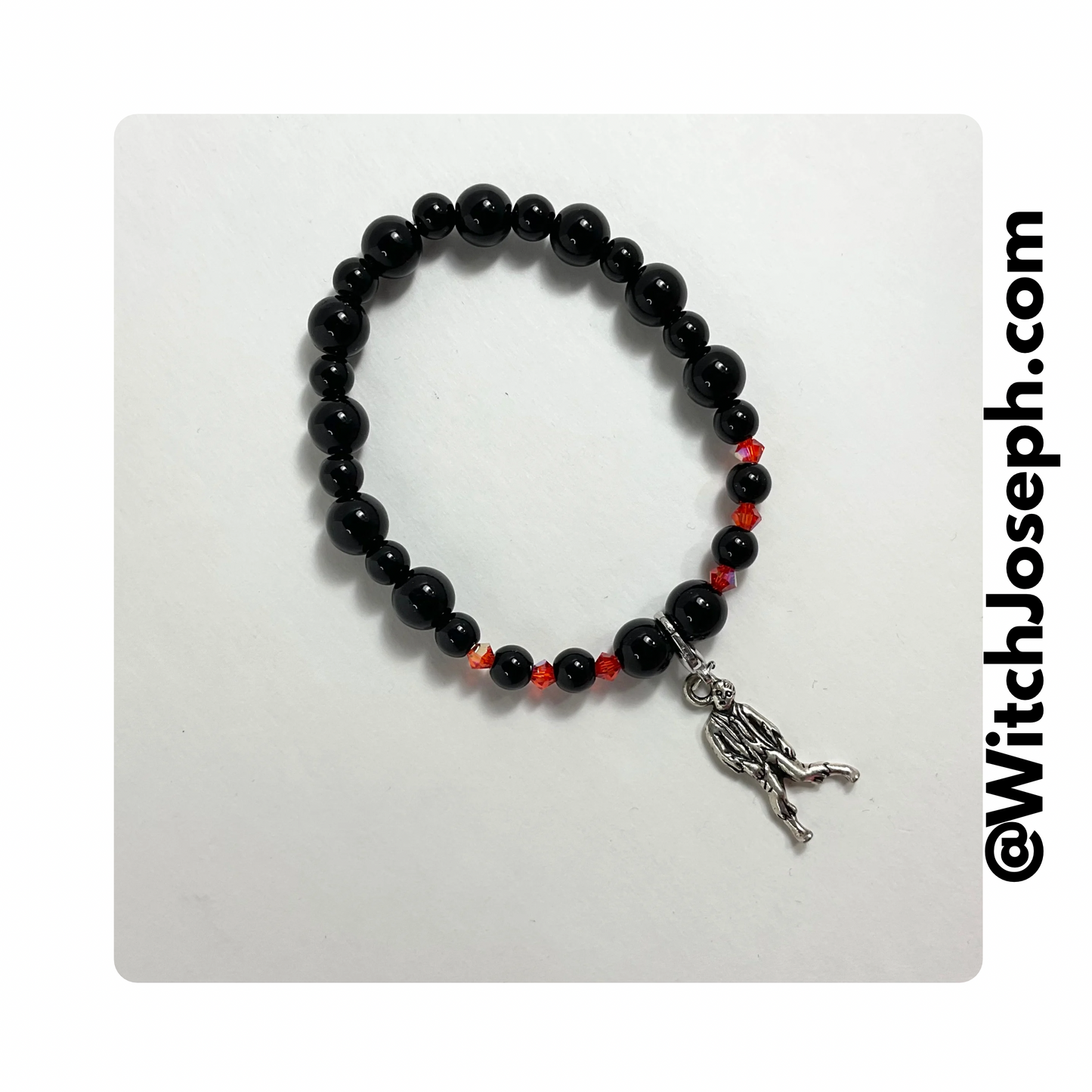 Halloween stretch bracelet with orange and black beads with a zombie charm displayed against a light background with the Witch Joseph url
